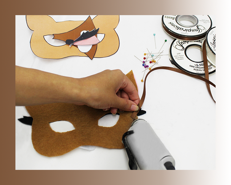 Closeup of ribbon being attached to the deer felt mask